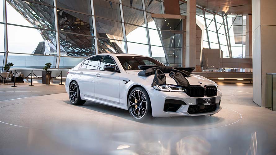Weisser BMW M5 mit schwarzer Schleife auf der Abholungsplattform der BMW Welt