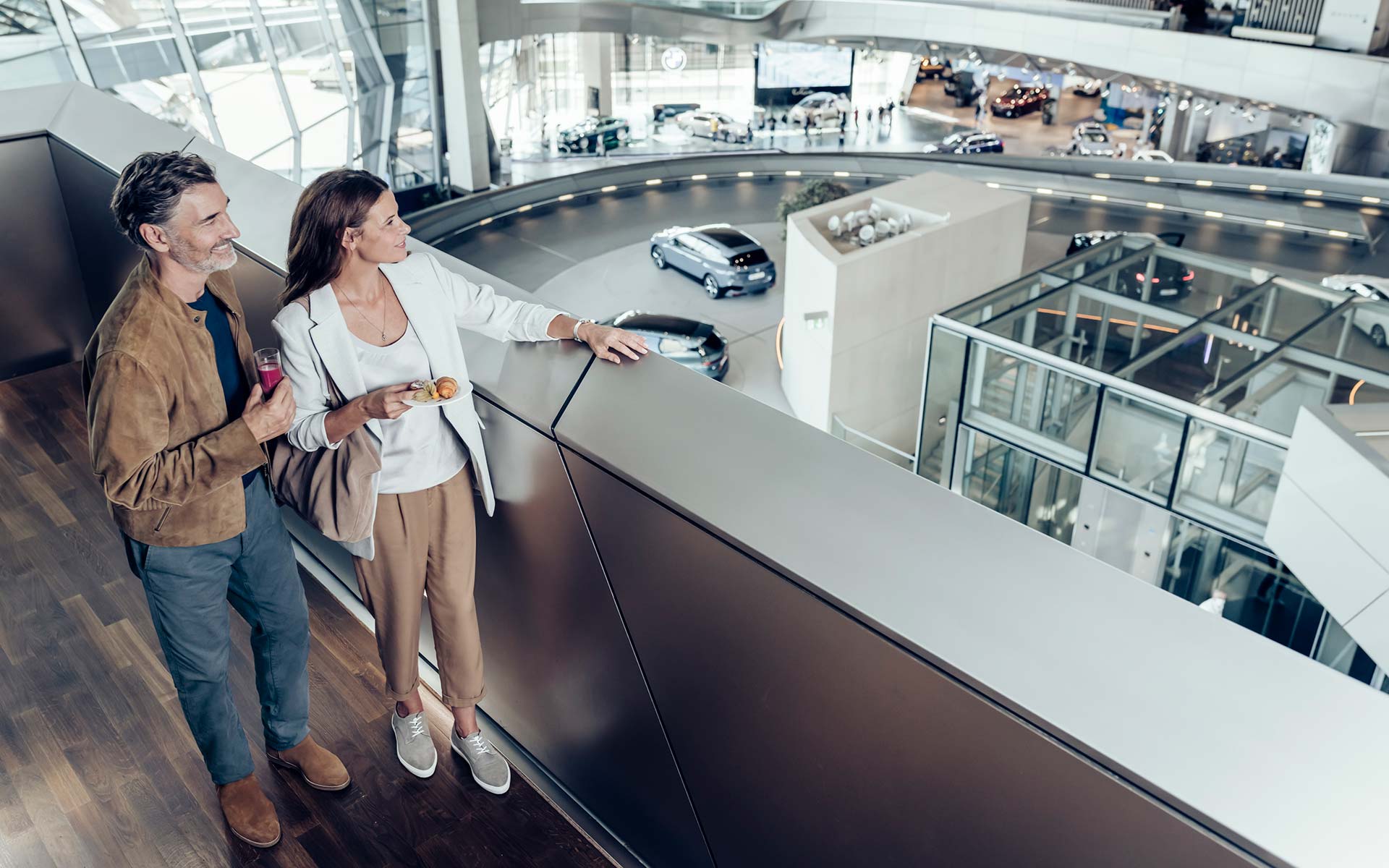 Happy couple enjoying the view from the gallery of the vehicles ready for pickup at BMW Welt