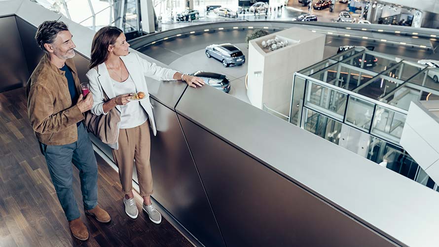 Glückliches Paar geniesst den Ausblick von der Galerie auf die zur Abholungbereitgestellten Fahrzeuge in der BMW Welt