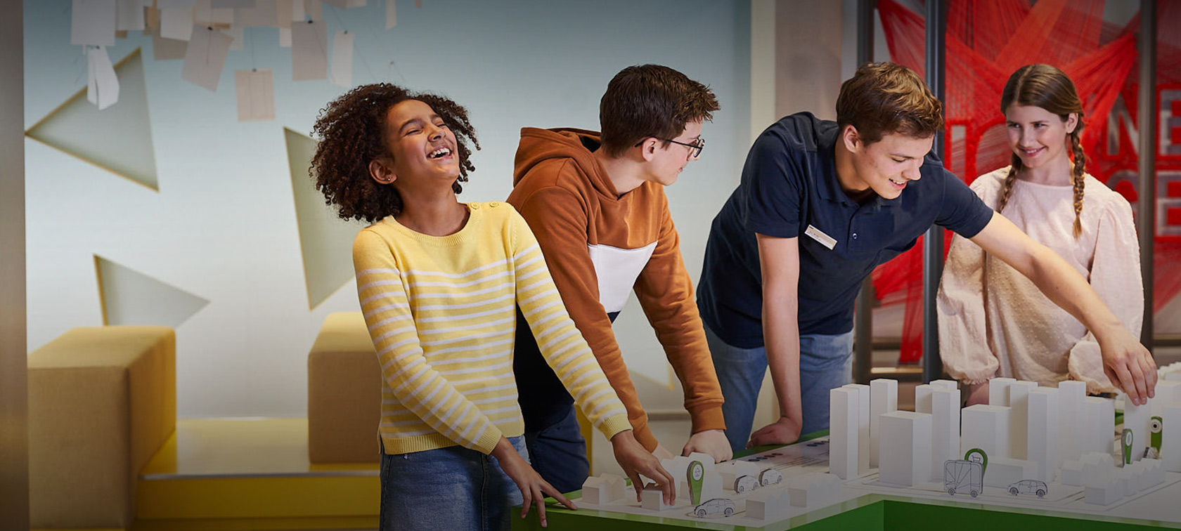 Children are building a model city with an BMW Welt workshop attendant