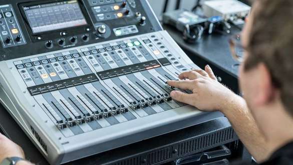 Audiotechnik Mann verschiebt Schieberegler auf einem Soundboard im BMW Welt Business Center
