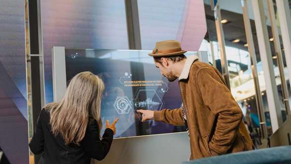 happy woman operates infoscreen in bmw welt exhibition