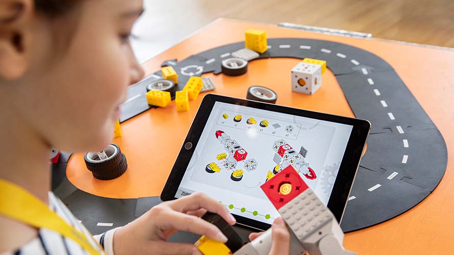 BMW Programmierworkshop 7-10 Jahre Mädchen baut Lego-Roboter mit Hilfe eines Bauplans auf einem Tablet