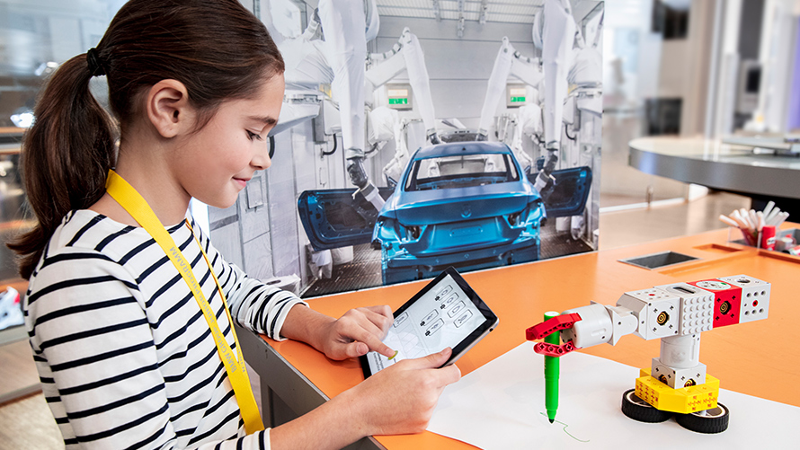BMW Klassen- und Gruppenausflüge Programmierworkshop Mädchen steuert einen kleinen Lego-Roboter mit Hilfe eines Tablets