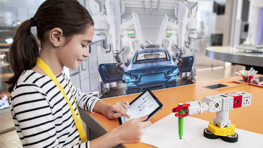 Programming workshops Girl controls a small Lego robot with the help of a tablet