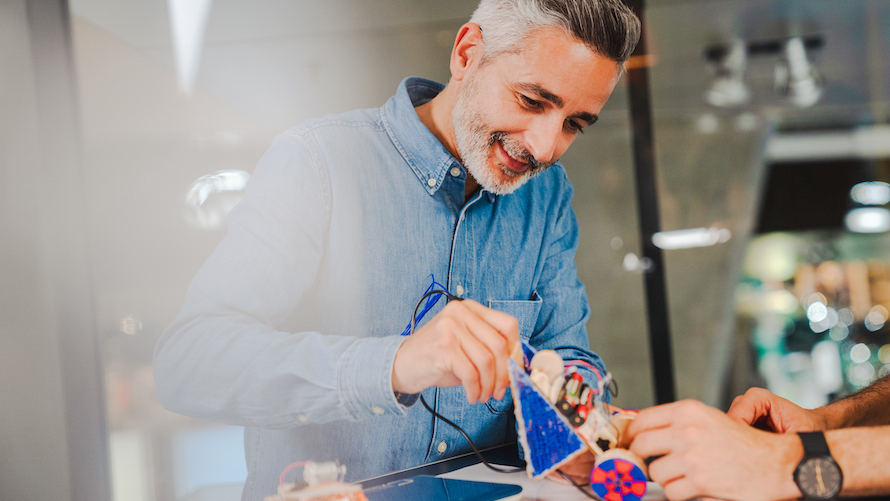 Mann lötet selbstgebautes Automodell aus Holz und Motorisierung 