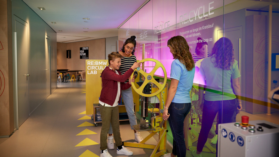 BMW Familien und Kinder Circular Lab Kind dreht Rad an einer Maschine im BMW Nachhaltigkeits-Workshop