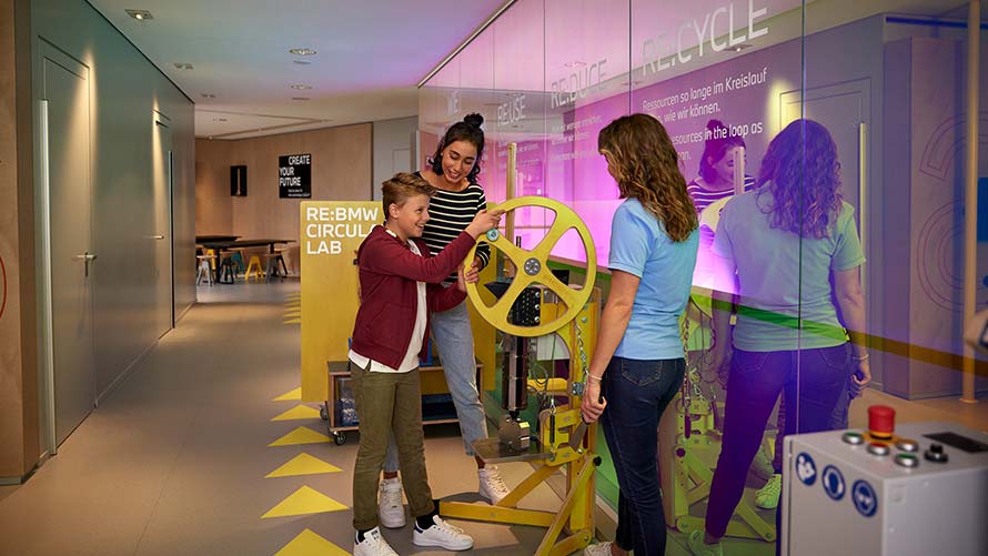 BMW Klassen- und Gruppenausflüge Circular Lab Kind dreht Rad an einer Maschine im BMW Nachhaltigkeits-Workshop